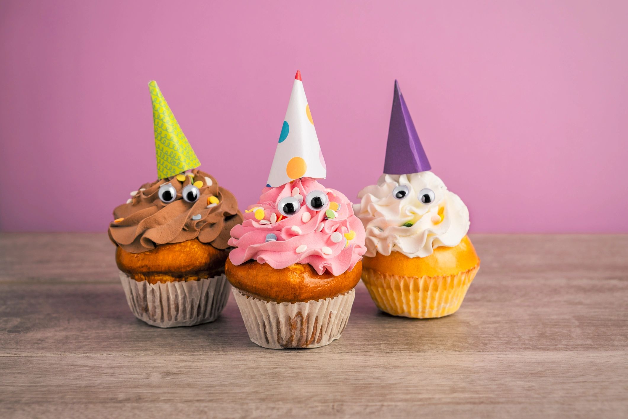 Playful cupcakes decorated with party hats and googly eyes.